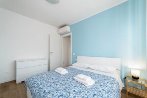 Camera matrimoniale con parete azzurra aria condizionata e comodini appartamento vacanze Monza