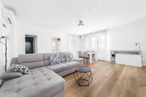 Soggiorno con divano grigio tavolo pranzo e TV parquet appartamento vacanze
