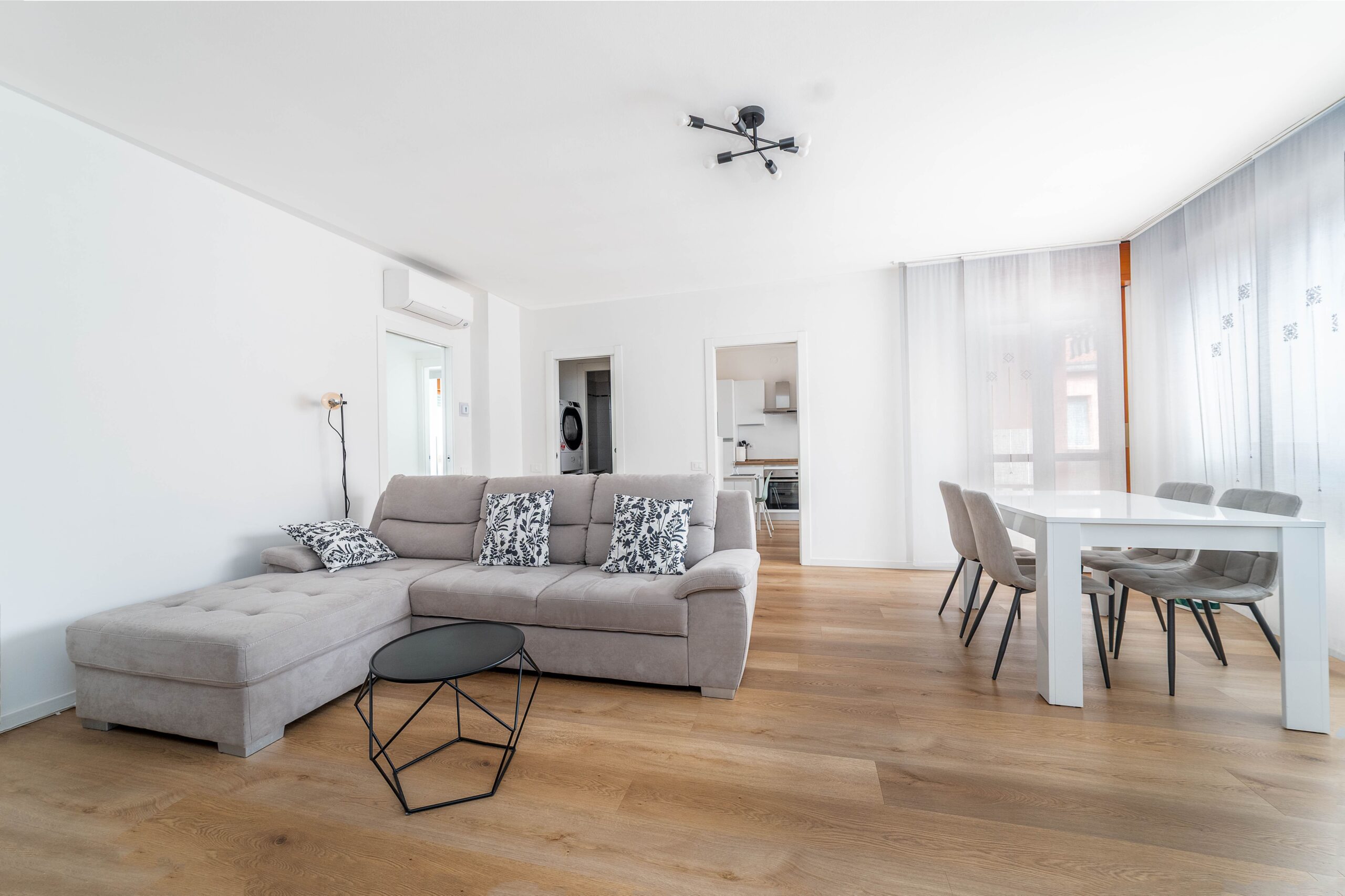 Soggiorno con divano grigio tavolo pranzo e TV parquet appartamento vacanze BNB Monza