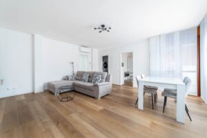 Soggiorno con divano grigio tavolo pranzo e TV parquet appartamento vacanze BNB Monza