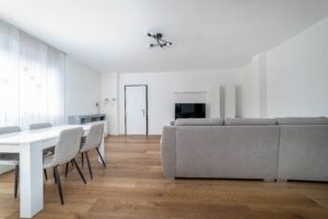 Soggiorno con divano grigio tavolo pranzo e TV parquet appartamento vacanze