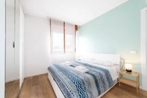 Camera matrimoniale con parete verde menta parquet e comodino legno appartamento vacanze Monza